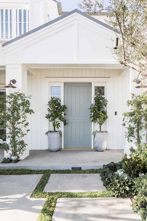 Entry to a home showing bilateral symmetry with two matching trees in matching planters